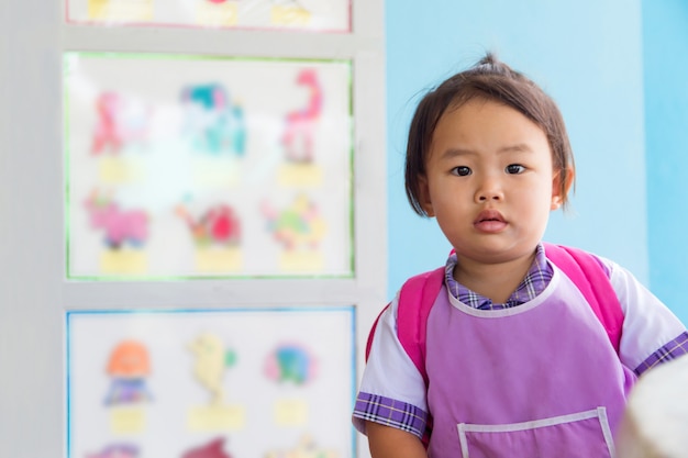 Azjatycki przedszkolak mała dziewczynka uczeń w mundurze ogólnym i czerwona torba idzie do szkoły