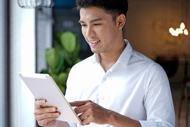 Azjatycki przystojny biznesmen lub młody student za pomocą komputera typu tablet