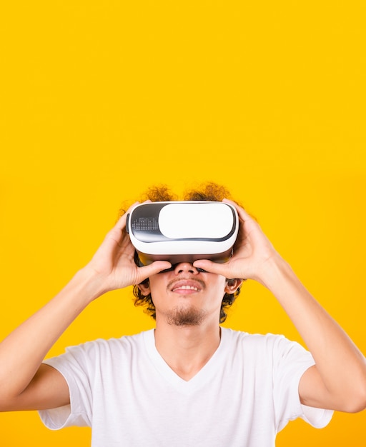 Azjatycki przystojny mężczyzna z kręconymi włosami on używa wirtualnej rzeczywistości słuchawki lub szkła VR