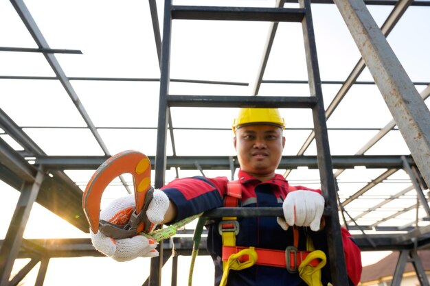 Azjatycki robotnik budowlany pracujący na wysokości Nosi sprzęt bezpieczeństwa i pasy bezpieczeństwa do pracy na dużych wysokościach na placu budowy