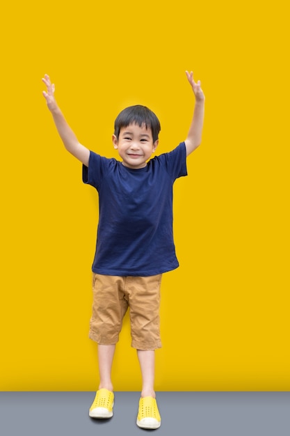 Azjatycki Śliczny chłopiec uśmiech, stojak z kolor żółty ściany tłem i