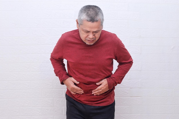 Azjatycki starszy mężczyzna cierpiący na ból żołądka, problem z trawieniem lub refluks żołądkowy