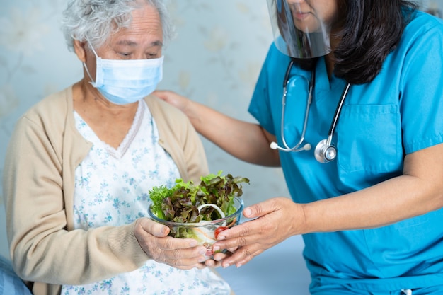 Azjatycki starszy pacjentka kobieta trzyma warzywo w szpitalu.