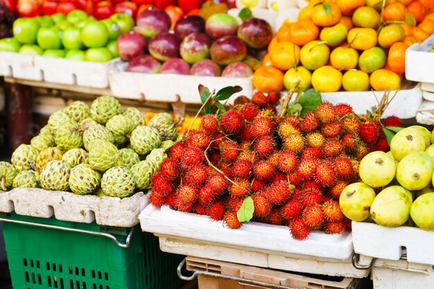 Azjatycki targ uliczny ze świeżymi owocami i jagodami w Hoi An w Wietnamie. Marakuja, liczi, czerymoja, mango i inne. Kolory czerwony, pomarańczowy i zielony.