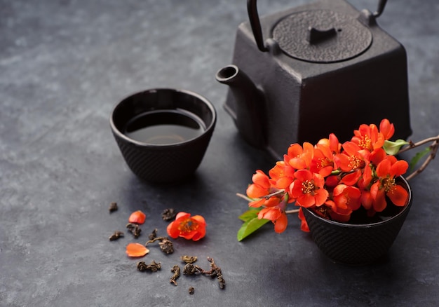 Azjatycki żeliwny zestaw do herbaty z zieloną herbatą Zielona herbata i kwiaty czarne tło