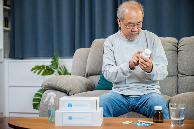Azjatycki zmartwiony starszy mężczyzna z tabletkami lekarskimi, o których czytał, aby zobaczyć, jak brać pigułki przed zażyciem