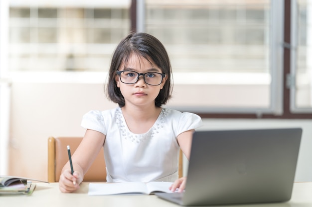 Azjatyckie dzieci dziewczyna studentka z okularami studiuje online, odrabiania lekcji na laptopie w domu. Koncepcja edukacji Stock Photo