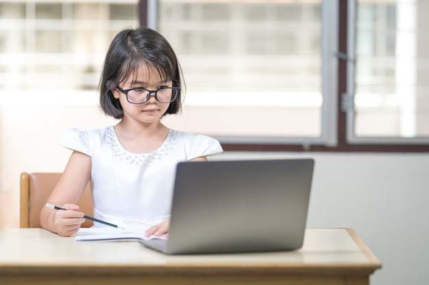 Azjatyckie dzieci dziewczyna studentka z okularami studiuje online, odrabiania lekcji na laptopie w domu. Koncepcja edukacji Stock Photo