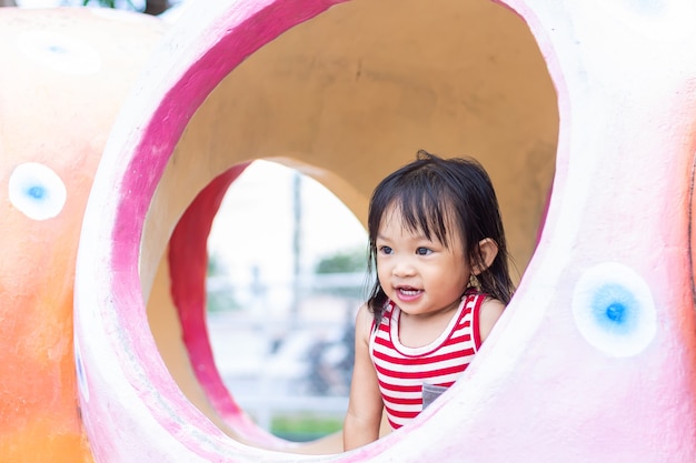 Azjatyckie dziecko dziewczyna uśmiechając się i śmiejąc się. Bawi się zabawką na placu zabaw w parku.
