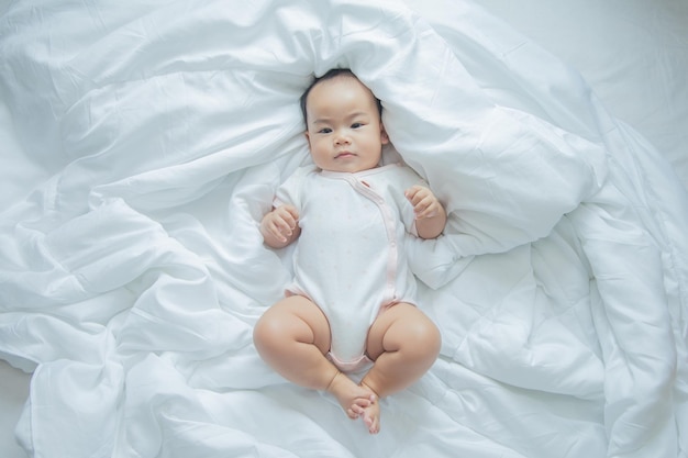 Azjatyckie dziecko leżące na łóżku z miękkim kocem w pomieszczeniu słodkie małe azjatyckie noworodek