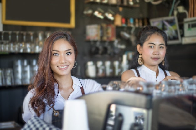 Azjatyckie kobiety Barista uśmiecha się i przy użyciu ekspres do kawy w kawiarni licznik - kobieta pracująca mały bu
