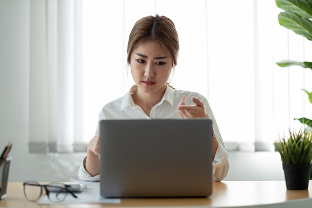 Azjatyckie kobiety oglądając webinarium edukacyjne na laptopie. Uśmiechnięty młody biznesmen gospodarstwa rozmowy wideo z partnerami klientów.