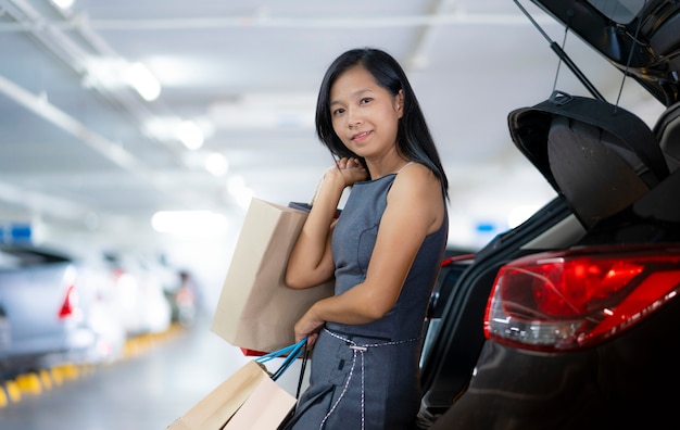 Azjatyckie kobiety trzymają torby na zakupy z tyłu samochodu