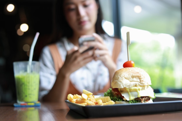 Azjatyckie kobiety uśmiechnięte i szczęśliwe i cieszyły się jedzeniem hamburgerów przy kawie i restauracji w czasie relaksu