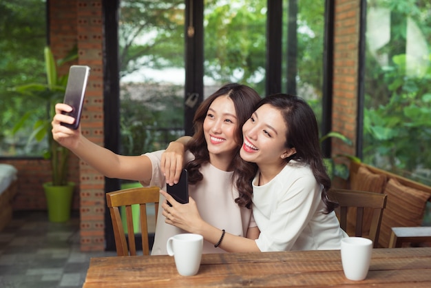 Azjatyckie koleżanki przytulają się i robią razem zdjęcie selfie