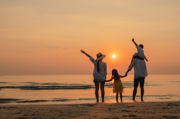 Azjatyckie rodzinne wakacje na wakacjeSzczęśliwi rodzice trzymający dzieci latające po niebie