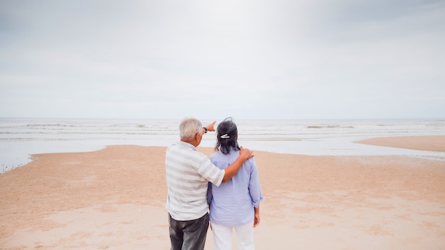 Azjatyckie stare starsze pary spacerujące po plaży nad morzem