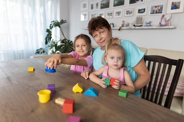 Babcia bawiąca się przy stole z wnukami w domu