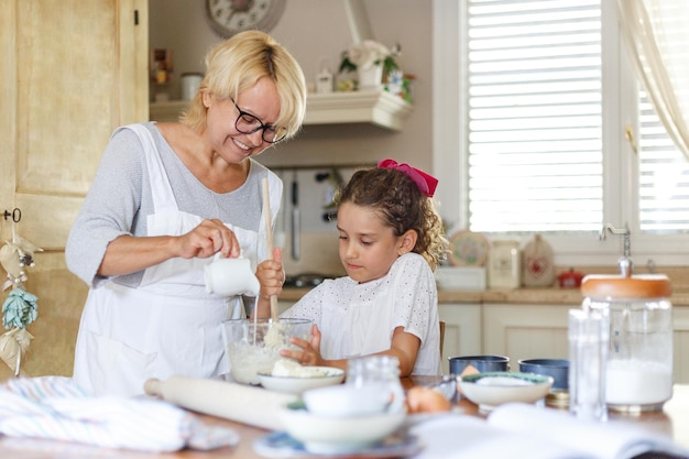 Babcia i urocza mała kędzierzawa wnuczka w kuchni przygotowują się razem.