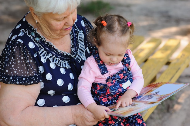 Babcia i wnuczka czytają książkę w parku