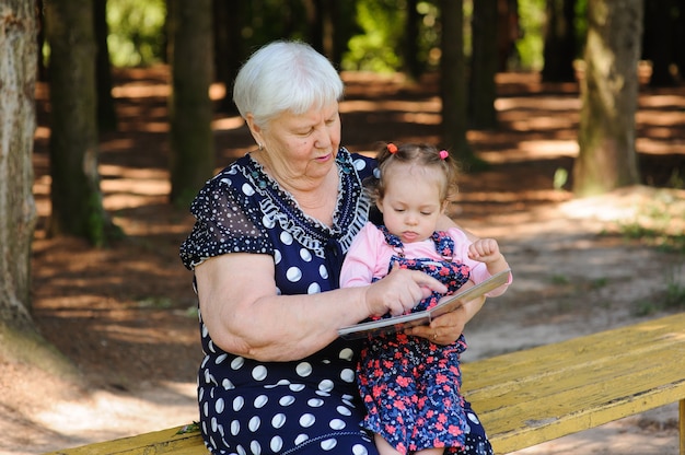 Babcia i wnuczka czytają książkę w parku