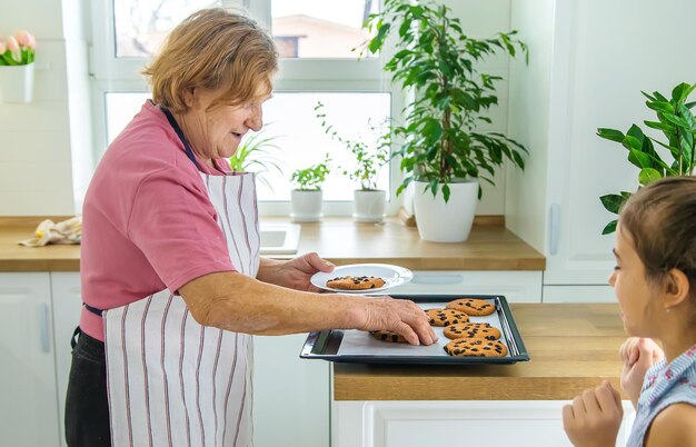 Zdjęcie babcia i wnuczka pieką ciasteczka w kuchni selektywne skupienie