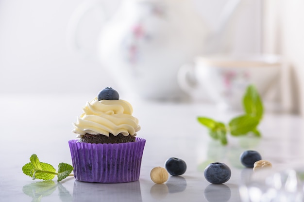 Babeczka Z Czarną Jagodą I Hazelnut W Purpurowym Opakunku Na Białym Naturalnym Marmurowym Biurku.