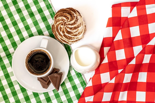Babeczki z gorzkiej czekolady i czekolady kakaowej z filiżanką gorącej czarnej kawy na zielonej i czerwonej serwetce Miejsce na tekst