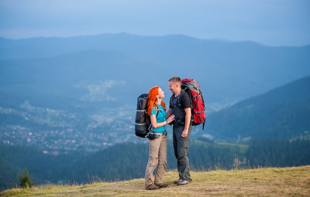 Backpackers facet i rudowłosa dziewczyna stoi