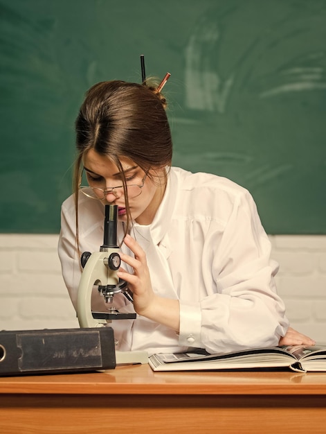 Zdjęcie badania laboratoryjne mądry uczeń patrzy w mikroskop w szkolnym laboratorium piękna kobieta prowadząca badania laboratoryjne w dziedzinie chemii lub biologii dostarczona z nowym nowoczesnym sprzętem laboratoryjnym