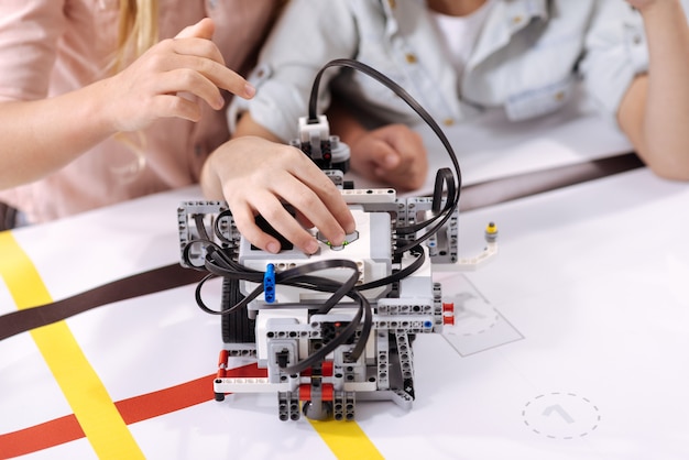 Zdjęcie badania techniczne. utalentowani zdolni zaangażowani dzieci siedzące w szkole i cieszące się klasą podczas konstruowania robota