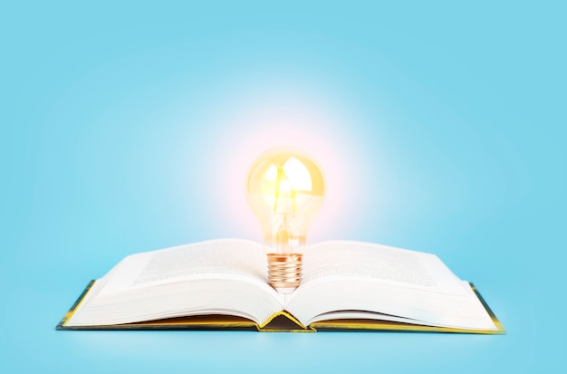 Badanie wiedzy koncepcja uczenia się otwarta książka ze świecącą żarówką na niebieskim tle badania r...