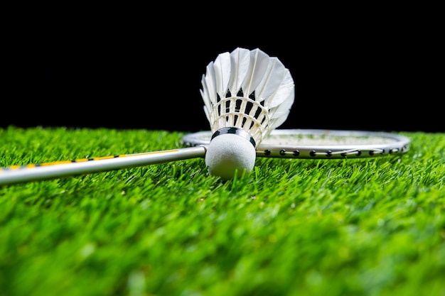 Badminton piłka i rakieta na trawie w czarnym tle
