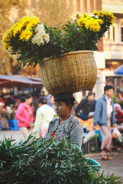 Zdjęcie bagan, mjanmar 3 lutego 2017 mjanmarska kobieta z proszkiem thanakha na twarzy i koszem kwiatów na głowie
