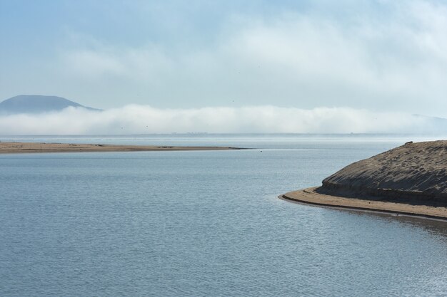 Bagno rzeki Ebro z chmurą mgły w tle i plaża na pierwszym planie