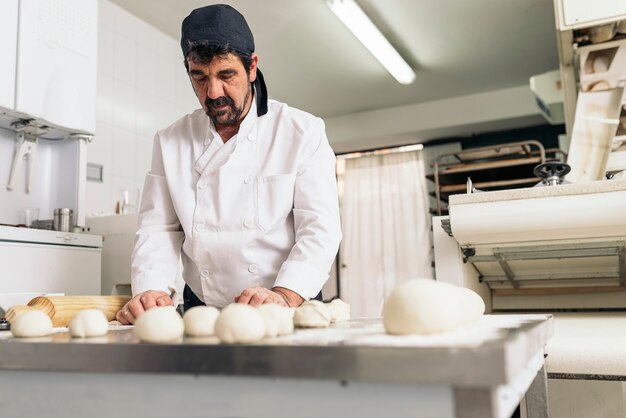 Baker wyrabiania ciasta w piekarni. Koncepcja piekarni.