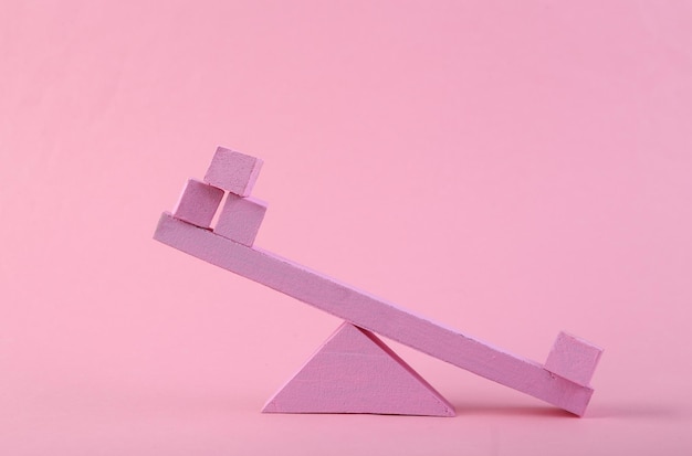 Zdjęcie balansująca huśtawka z kostkami na różowym tle równowaga minimalizm pastelowy trend kolorystyczny