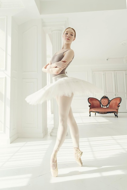 balerina w garniturze i tutu w pokoju przy oknie pokazuje kroki i elementy baletu