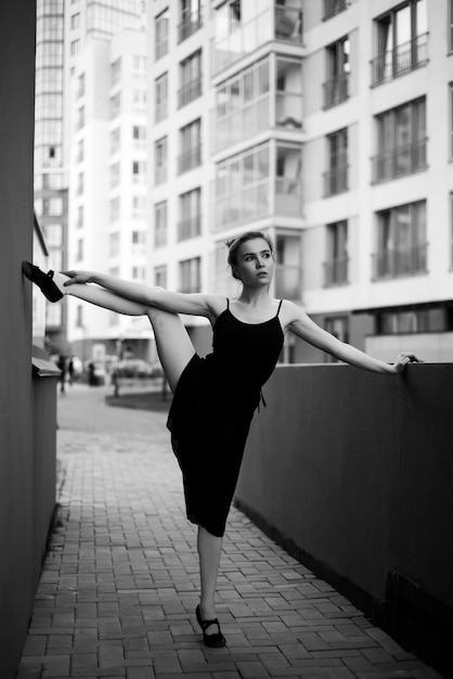 Balerina w tutu robi elegancką pozę Piękna młoda kobieta w czarnej sukience i pointe tańczy na tle miasta Portret wspaniałej baletnicy wykonującej taniec na zewnątrz Czarno-biały