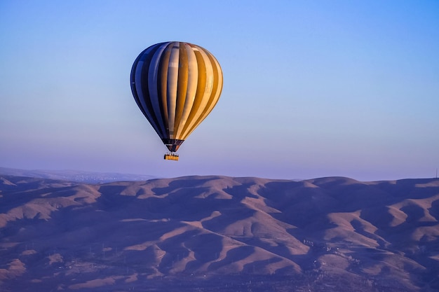 Balon na ogrzane powietrze lecący nad skalnym krajobrazem w Kapadocji, Turcja