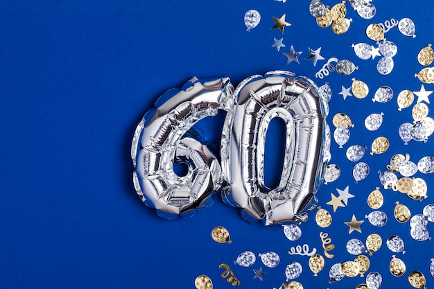 Balon ze srebrnej folii numer 60 na niebieskim tle z brokatowym gonfetti