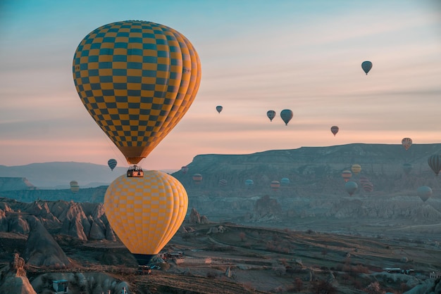 Balony na gorące powietrze latające nad górą na tle nieba podczas zachodu słońca