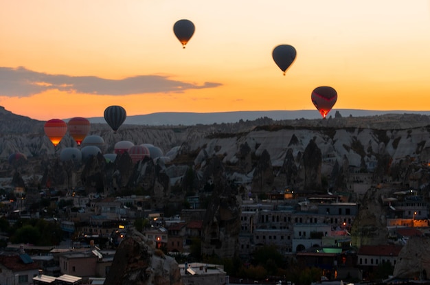 Balony na gorące powietrze latające nad krajobrazem miejskim podczas zachodu słońca