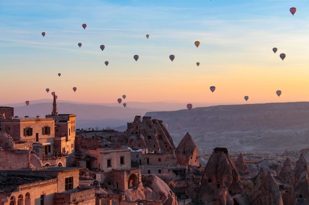 Balony na ogrzane powietrze wznoszą się wraz ze wschodem słońca w Kapadocji Turcja historyczne miejsce bajkowy komin