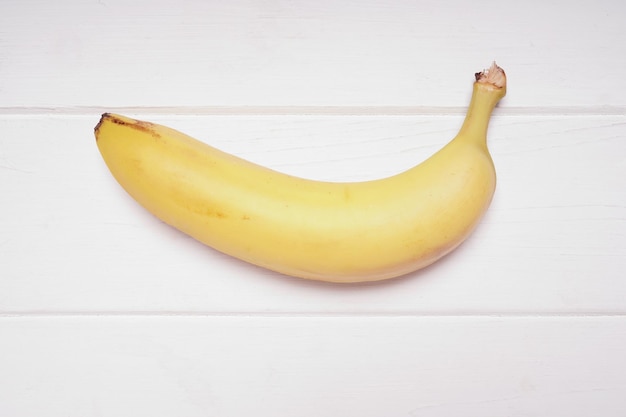Banan na nieociosanym białym drewnianym tle