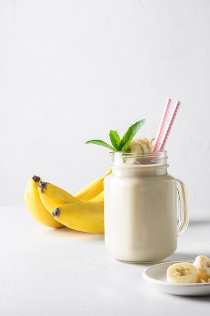 Bananowy milkshake na białej desce. Format pionowy