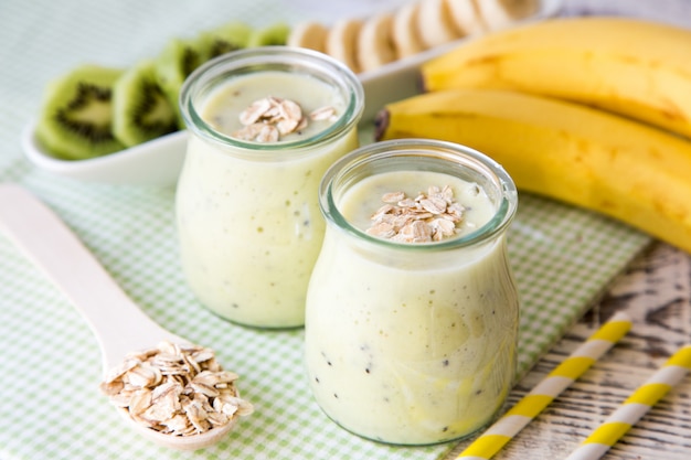 Bananowy smoothie z kiwi i owsami na lekkim drewnianym stole. Dieta białkowa. Koncepcja zdrowej żywności.