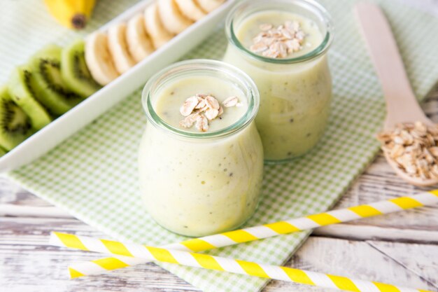 Bananowy smoothie z kiwi i owsami na lekkim drewnianym stole. Dieta białkowa. Koncepcja zdrowej żywności.