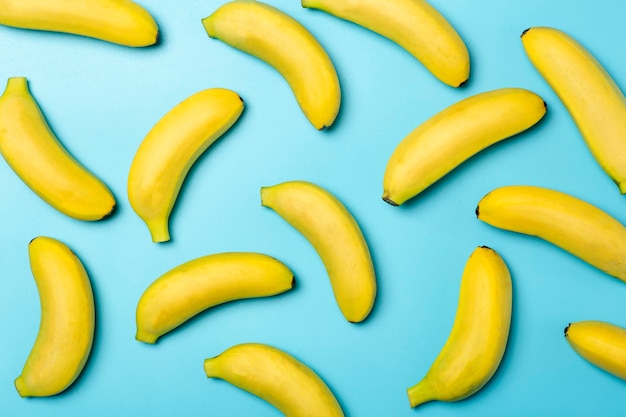 Banany na kolorowym tle. Wzór żółtych świeżych bananów na czystym niebieskim tle.
