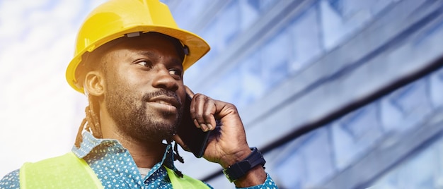 Baner inżyniera budowlanego mężczyzna pochodzenia afrykańskiego na zewnątrz rozmawiający przez telefon kopiować przestrzeń